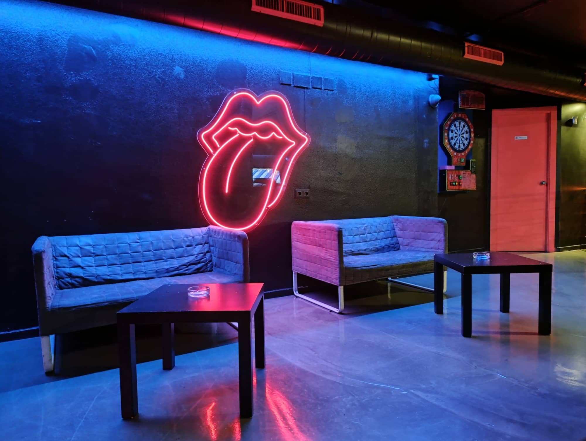 L'insegna al neon dei Rolling Stones illumina la hall di un cannabis social club di Barcellona, creando un'atmosfera vibrante.